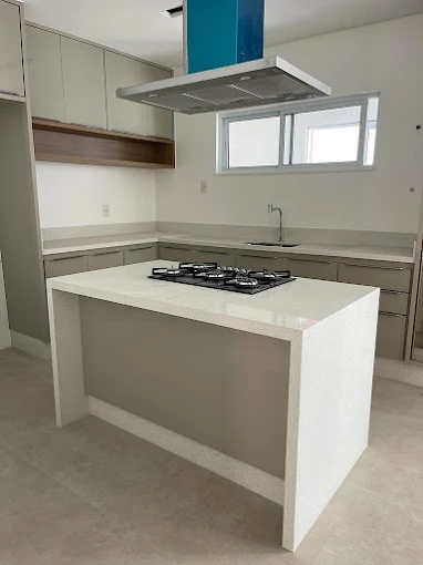 Ilha de cozinha com bancada em pedra clara e cooktop