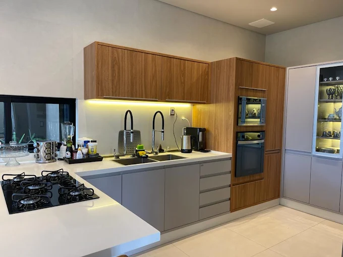 Cozinha com bancada em pedra clara e marcenaria em madeira