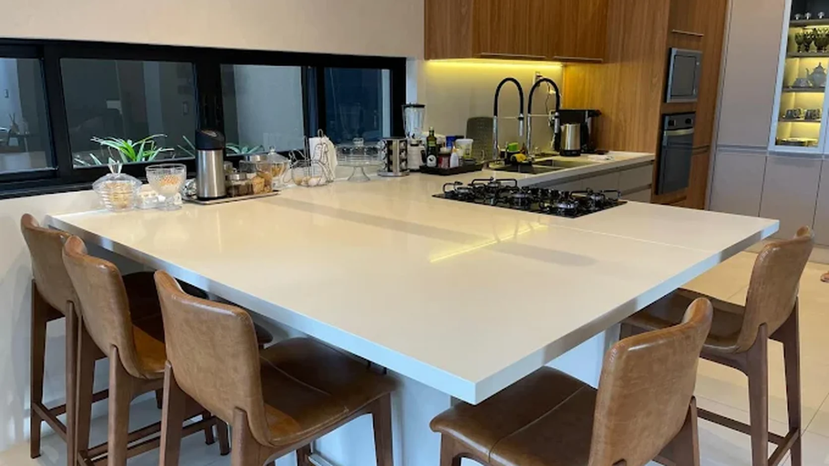 Ilha de cozinha com bancada ampla em pedra clara instalada pela Euromarmores