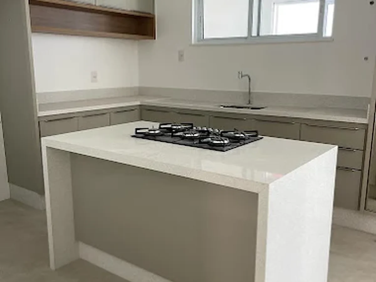 Ilha de cozinha com bancada em pedra clara e cooktop embutido